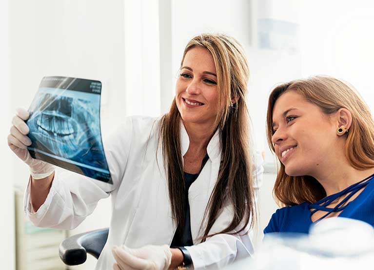 Female dentist showing x-rays to female patient. -767x554.jpg
