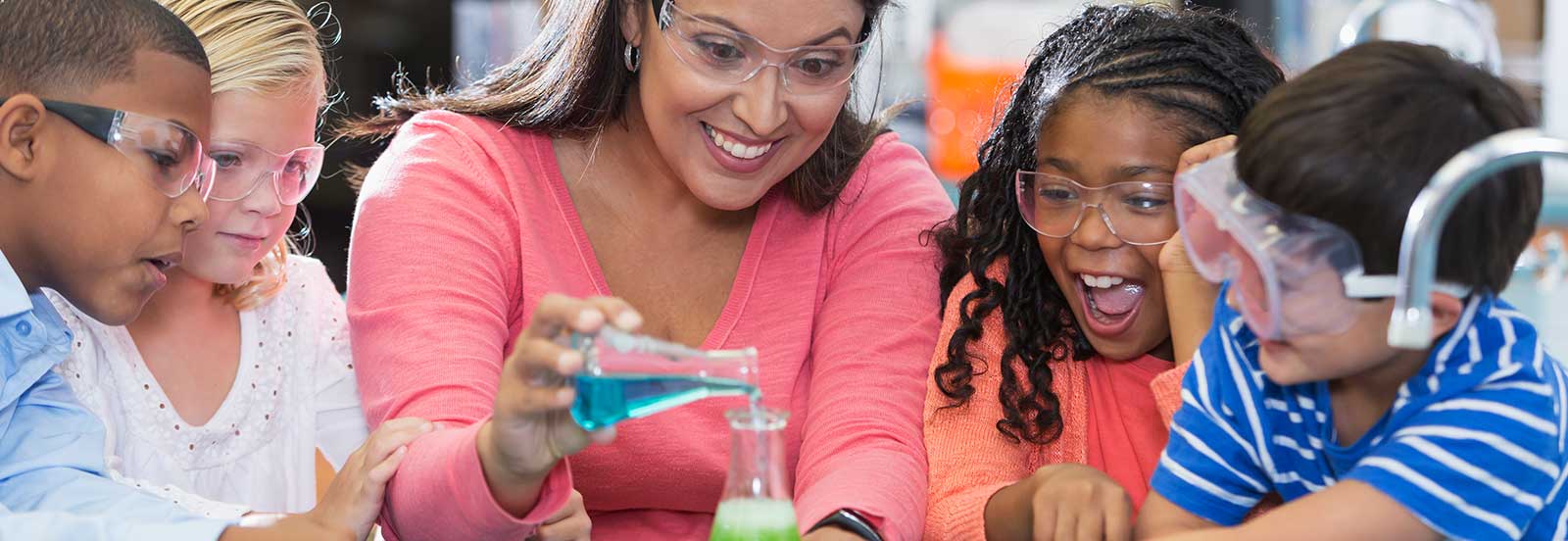 Female teacher showing young kids a science experiment. -1600x552.jpg