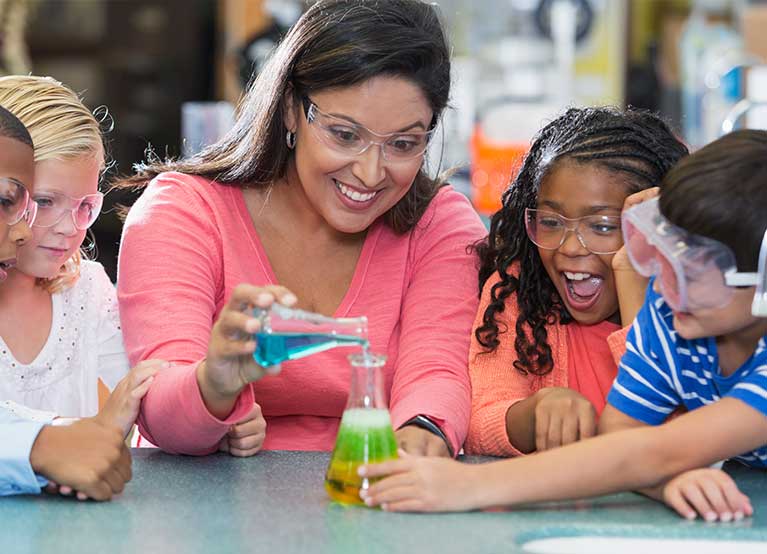 Female teacher showing young kids a science experiment. -767x554.jpg