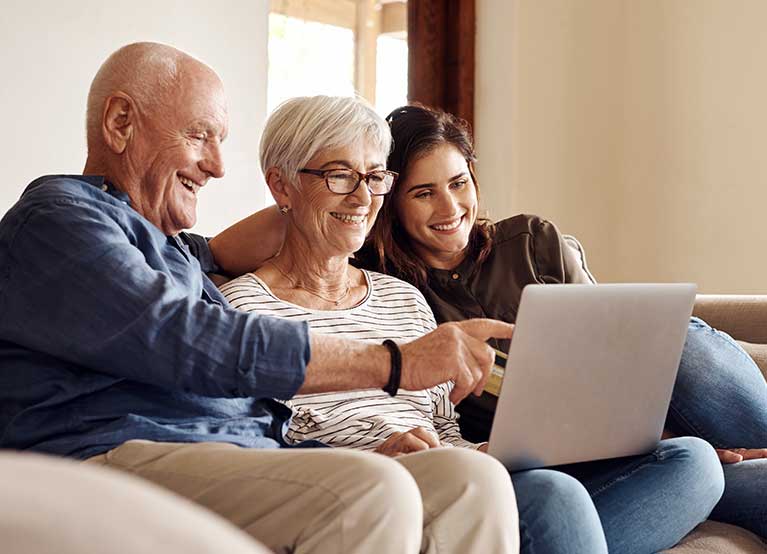 Older couple with a computer sitting next to a young lady on the couch. - 767x554.jpg